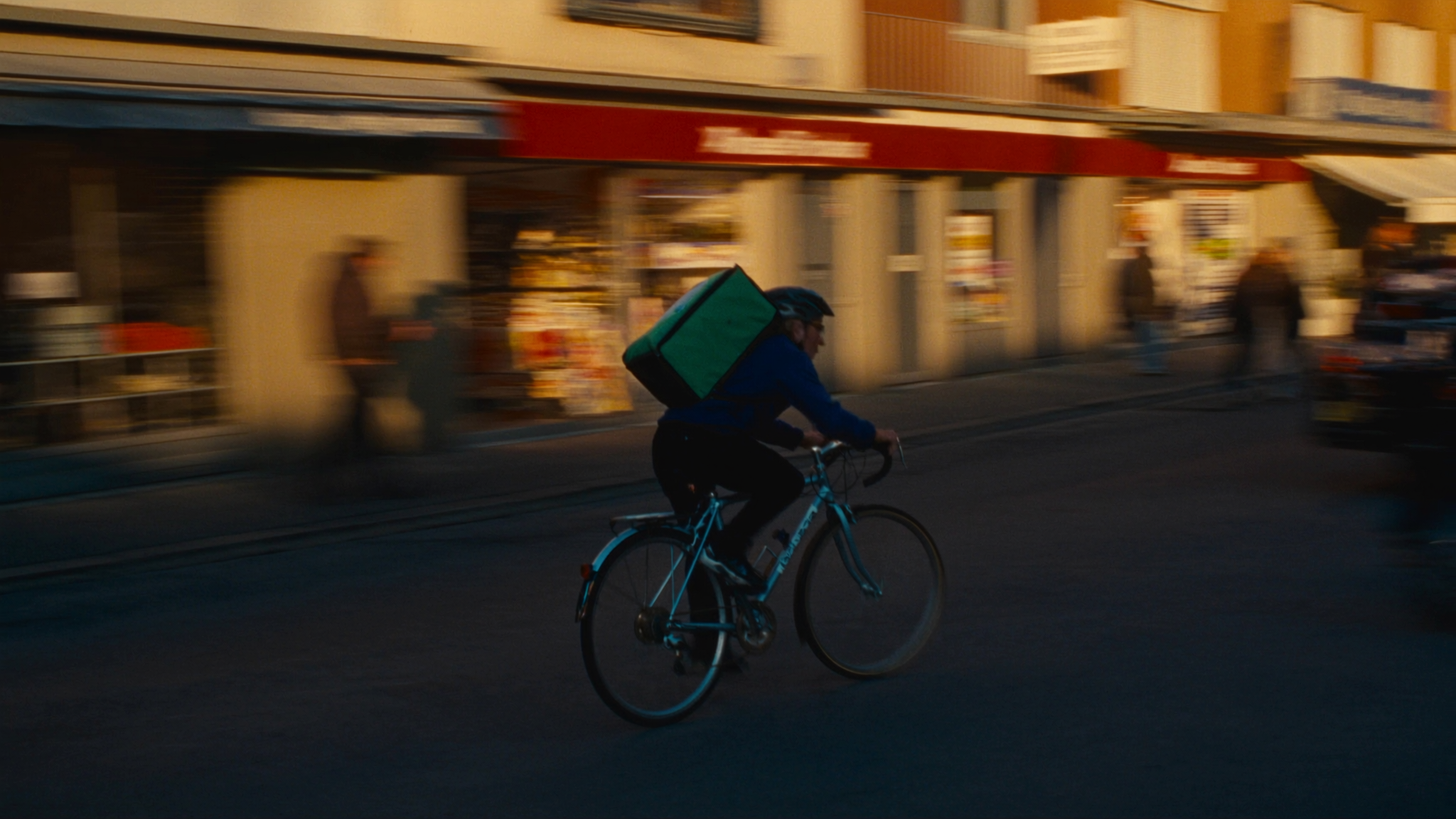 Velokurier fährt mit Tempo durch eine Schweizer Gasse, Bewegungsunschärfe, goldene Stunde